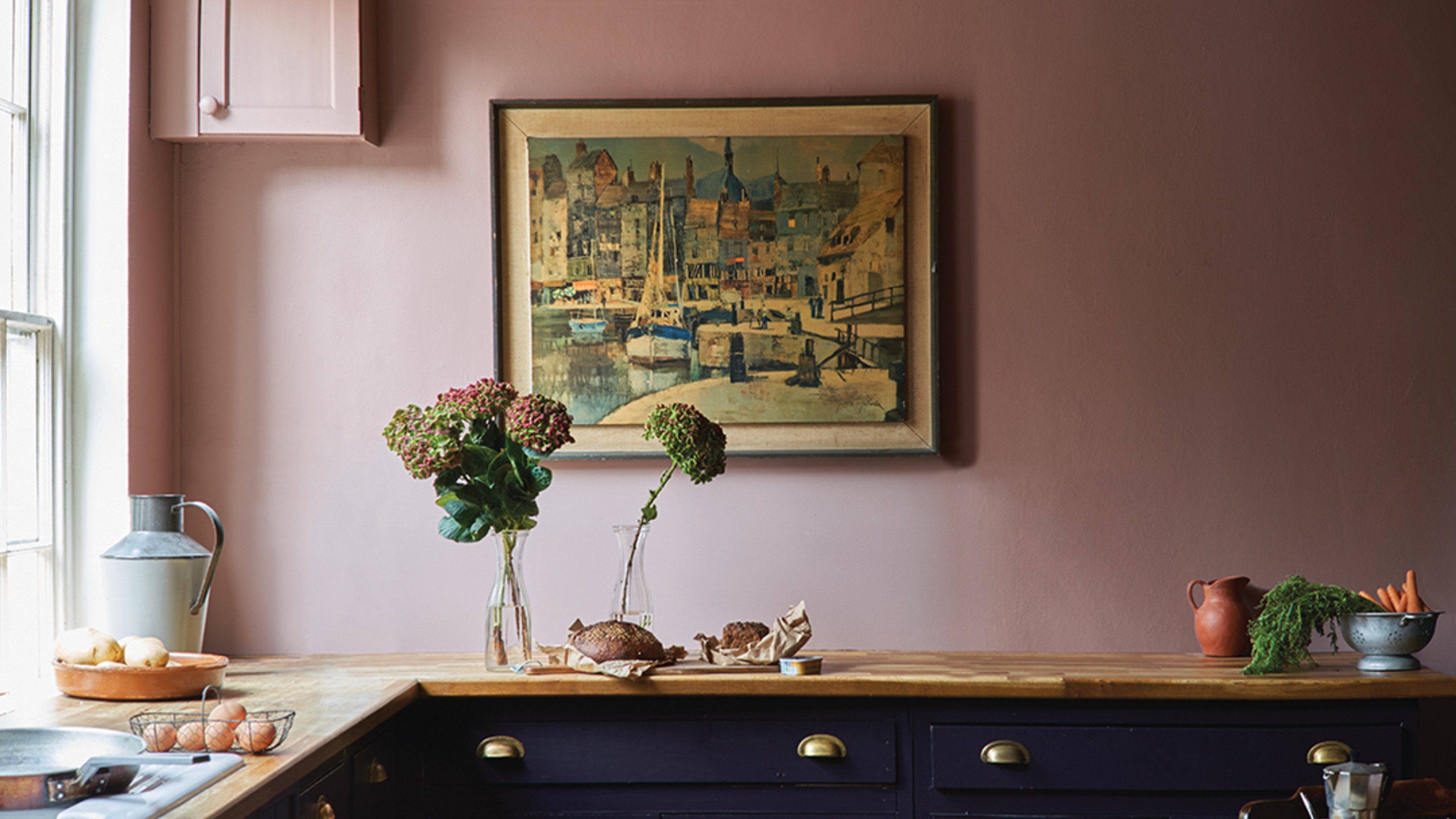 A kitchen with black cabinets and pink walls painted in Farrow & Ball's Sulking Room Pink