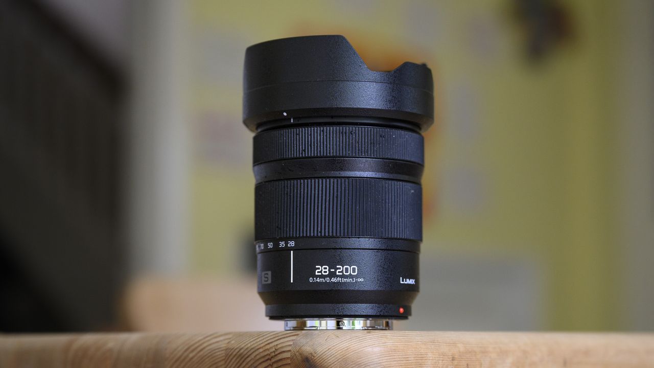 Panasonic Lumix S 28-200mm travel lens in on a wooden table with lens hood attached