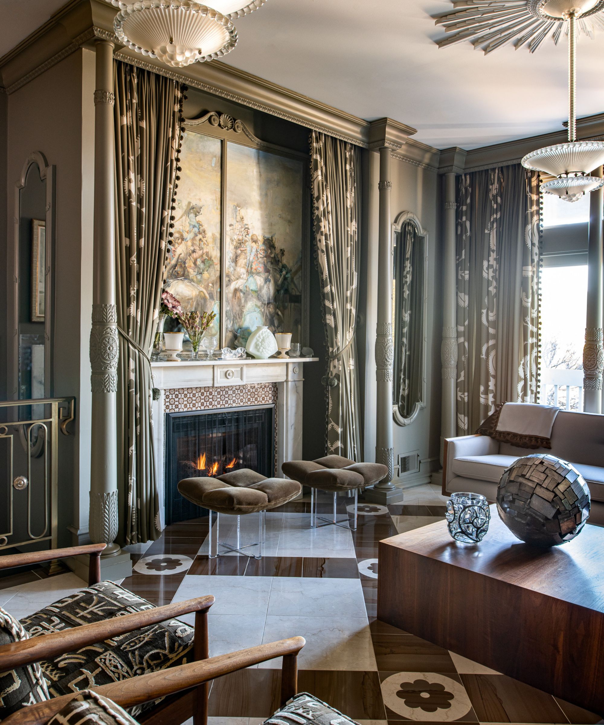 Living room with marble floor, ornate glass pendants, painting above fireplace, velvet stools and embroidered armchairs