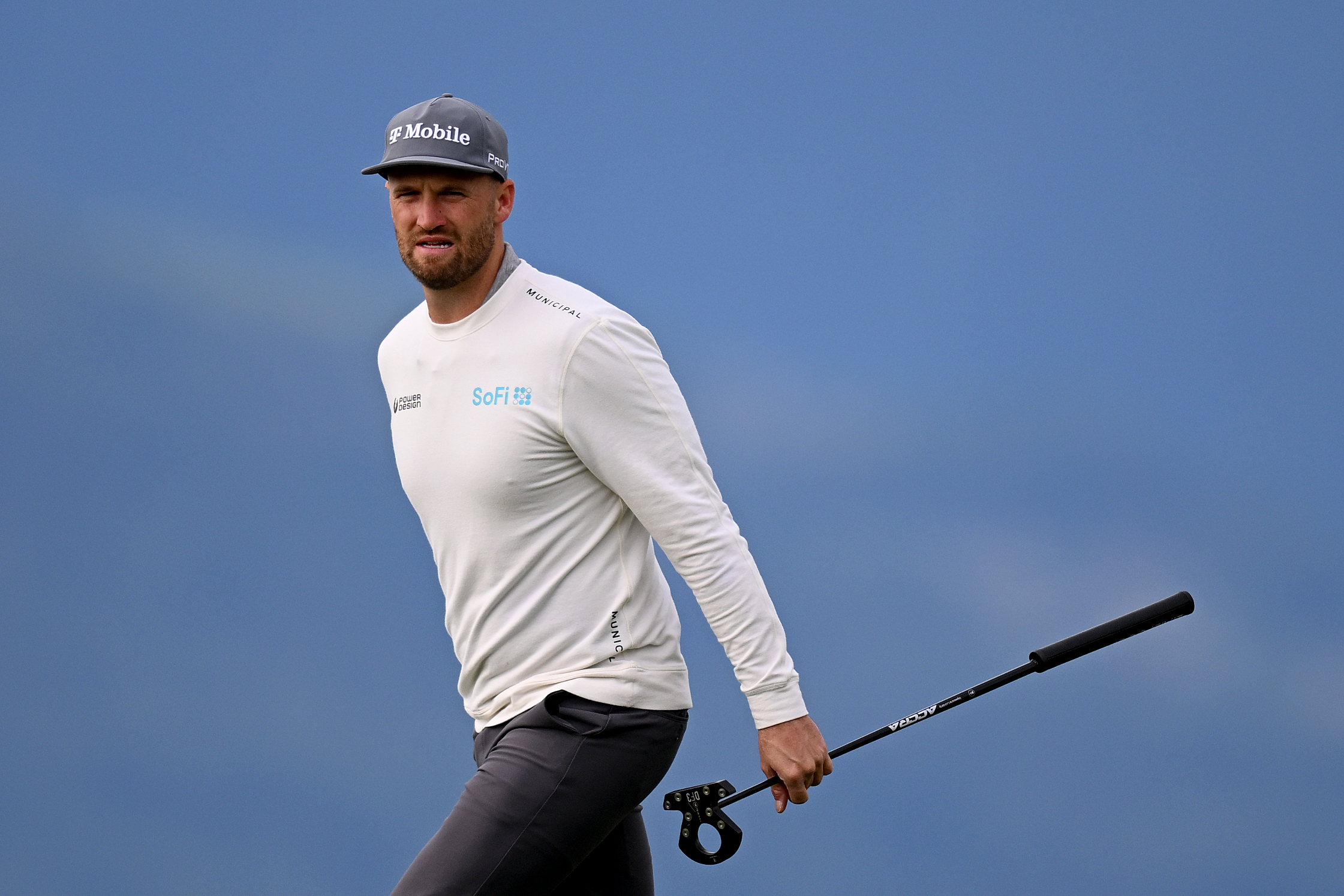 Wyndham Clark walks off the green holding a putter