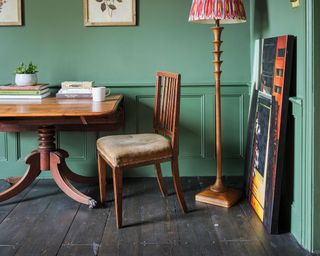 green paneled wall with wood dining table and a floor lamp