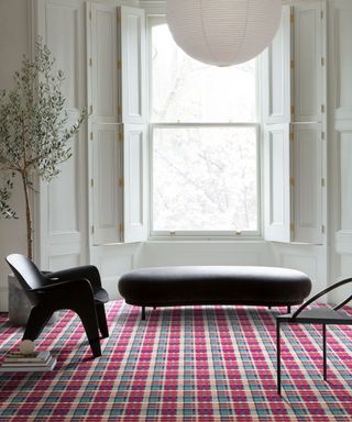 White, modern living room with round white lantern pendant, black furniture, bright red tartan carpet