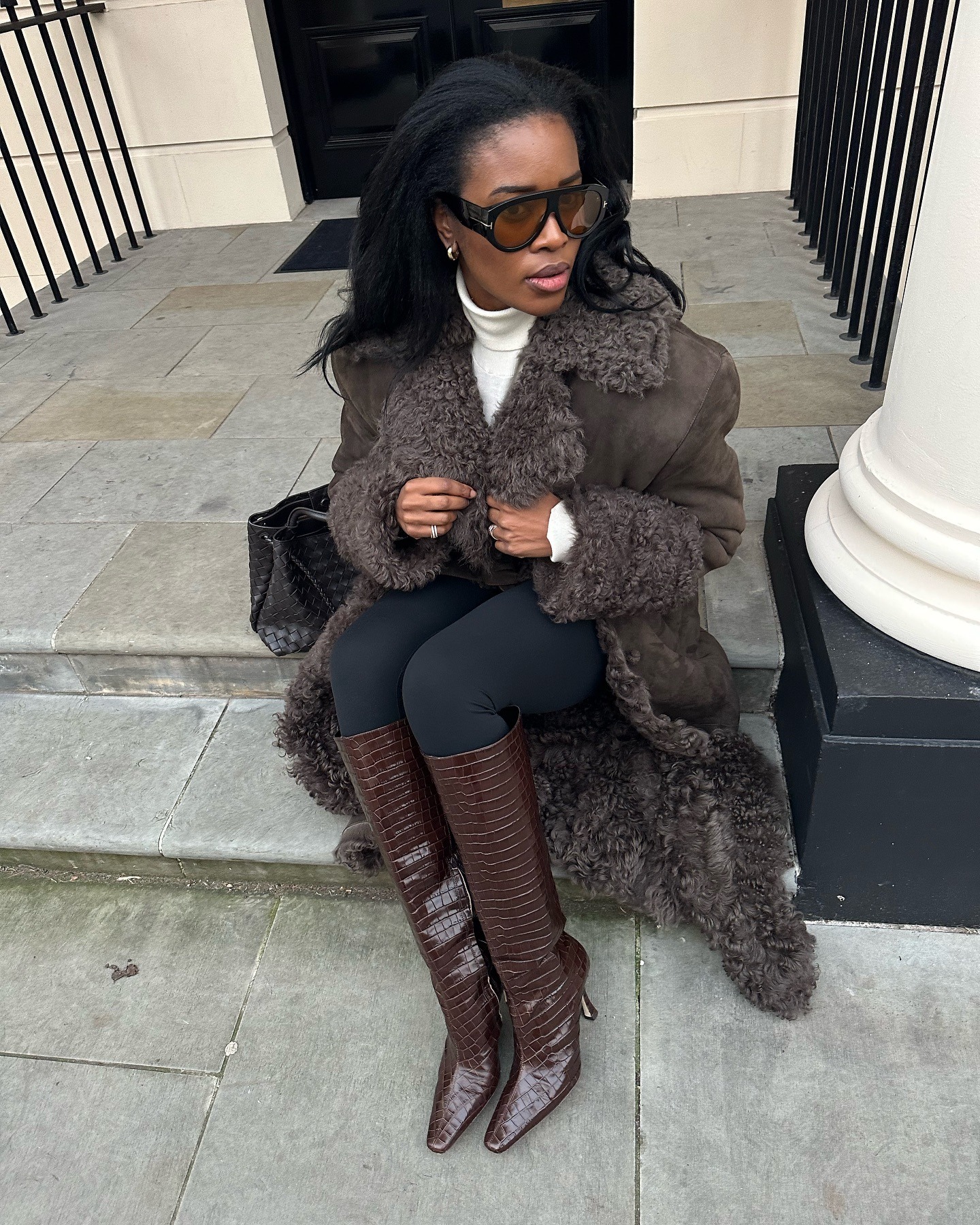 Fashion person Marylin wears a leggings outfit 2025. She wears a shearling trim jacket, black leggings and chocolate brown heeled boots.