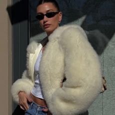 Hailey Bieber wearing a butter yellow Phoebe Philo shearling coat, a white tank top, vintage Levi's jeans, and beige heels from Jude.