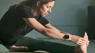 En kvinna som sitter och stretchar med en Garmin-klocka runt handleden.