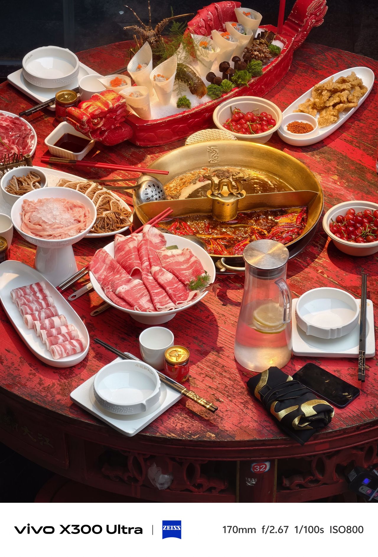 Overhead view of a large round table filled with sliced meats and ingredients around a hot pot.