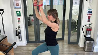 Woman performing resistance band shoulder flexion with lunge