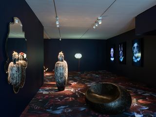 Dark room with circular seat and sculpture which is reflected through the mirror