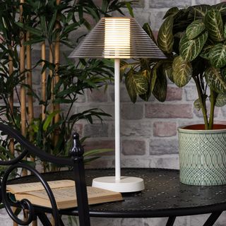 White outdoor table lamp on a wooden garden table
