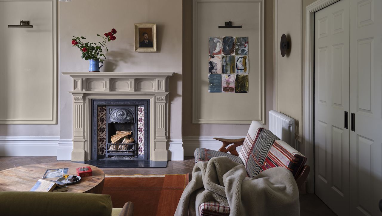 Farrow &amp; Ball color of the year 2024; a clay toned living room with a fireplace, pictures, and cozy couches