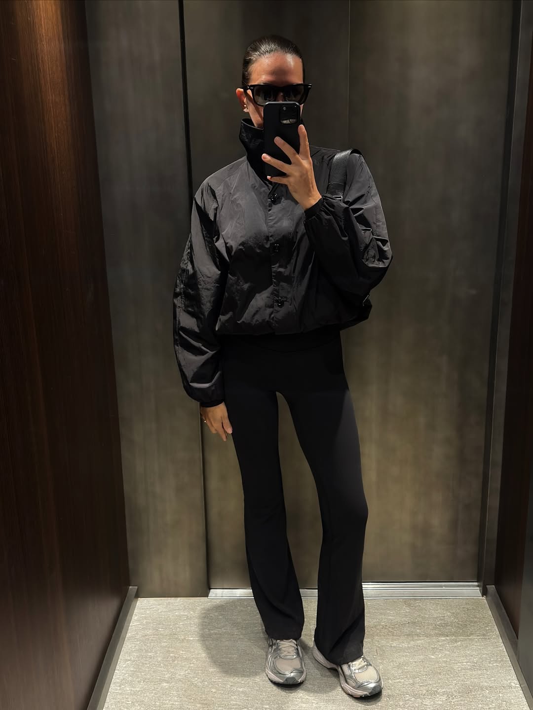 Elie Inoue wears a black tiered midi dress under a brown suede blazer with studded details, grey socks with silver sneakers, layered necklaces, and carries a black leather handbag outside Cecilie Bahnsen show during the Womenswear Spring Summer 2026 as part of Paris Fashion Week