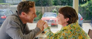 Benedict Cumberbatch and Olivia Colman holding hands while smiling at each other while at a restaurant in The Roses