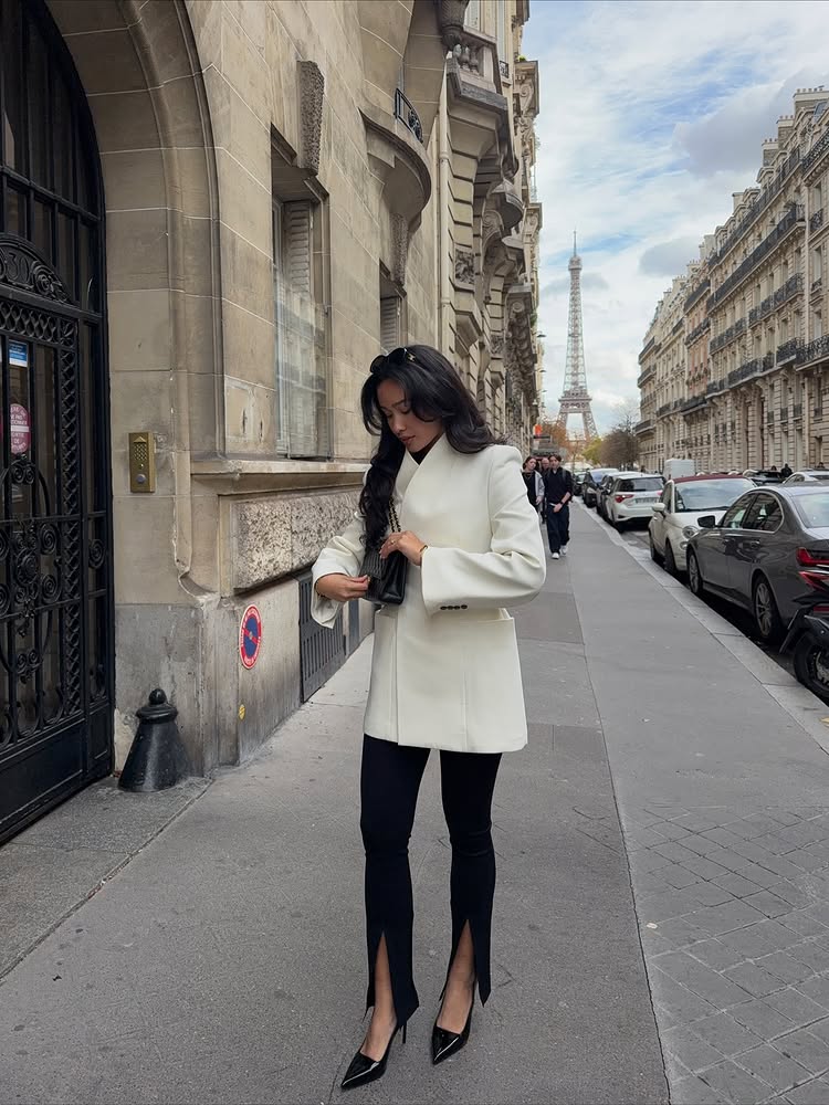 An image of @kristincabat wearing split-hem leggings, one of the biggest leggings trends for 2026, with an asymmetrical blazer and pointed-toe heels.