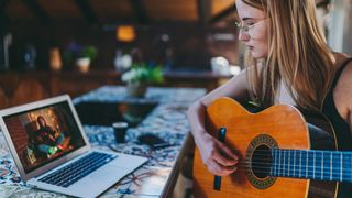 Girl pays classical guitar in front of her laptop