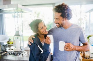 mixed race couple drinking coffee in kitchen