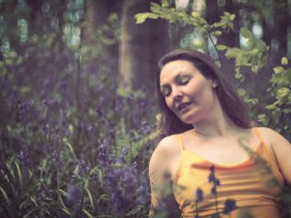Woman in a yellow dress, lying in a bluebell field with bokeh balls in the background. Shot on the OM System OM-1 Mark II with Pentax Super Takumar 50mm f/1.4 lens