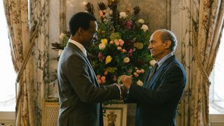 Sydney Johnson (Jude Akuwudike) and Mohamed Al Fayed (Salim Daw) hold hands in The Crown season 5 