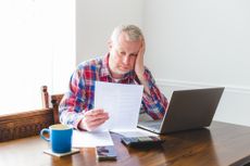 Worried man looking at paperwork at home
