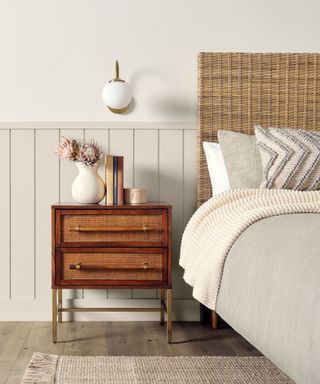 neutral bedroom with panelled wall, wicker headboard and wooden nightstand