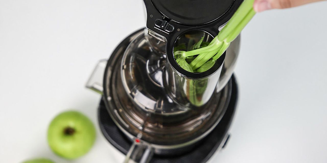 Image of Kuvings juicer being used to juice a green vegetable 