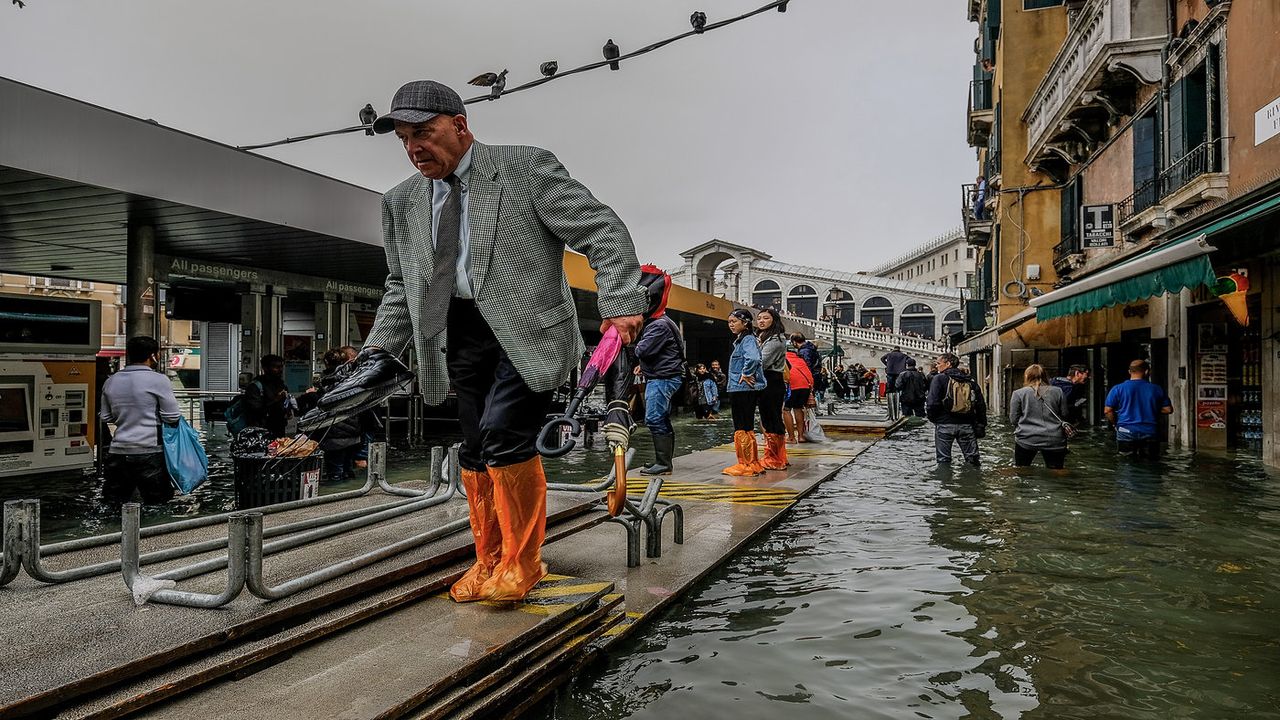 VENICE, ITALY - OCTOBER 29: People walk across temporary walkways following flooding caused by a high tide on October 29, 2018 in Venice, Italy. Due to the exceptional level of the "acqua alt