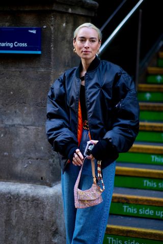 Influencer wears black leather bomber jacket with jeans.