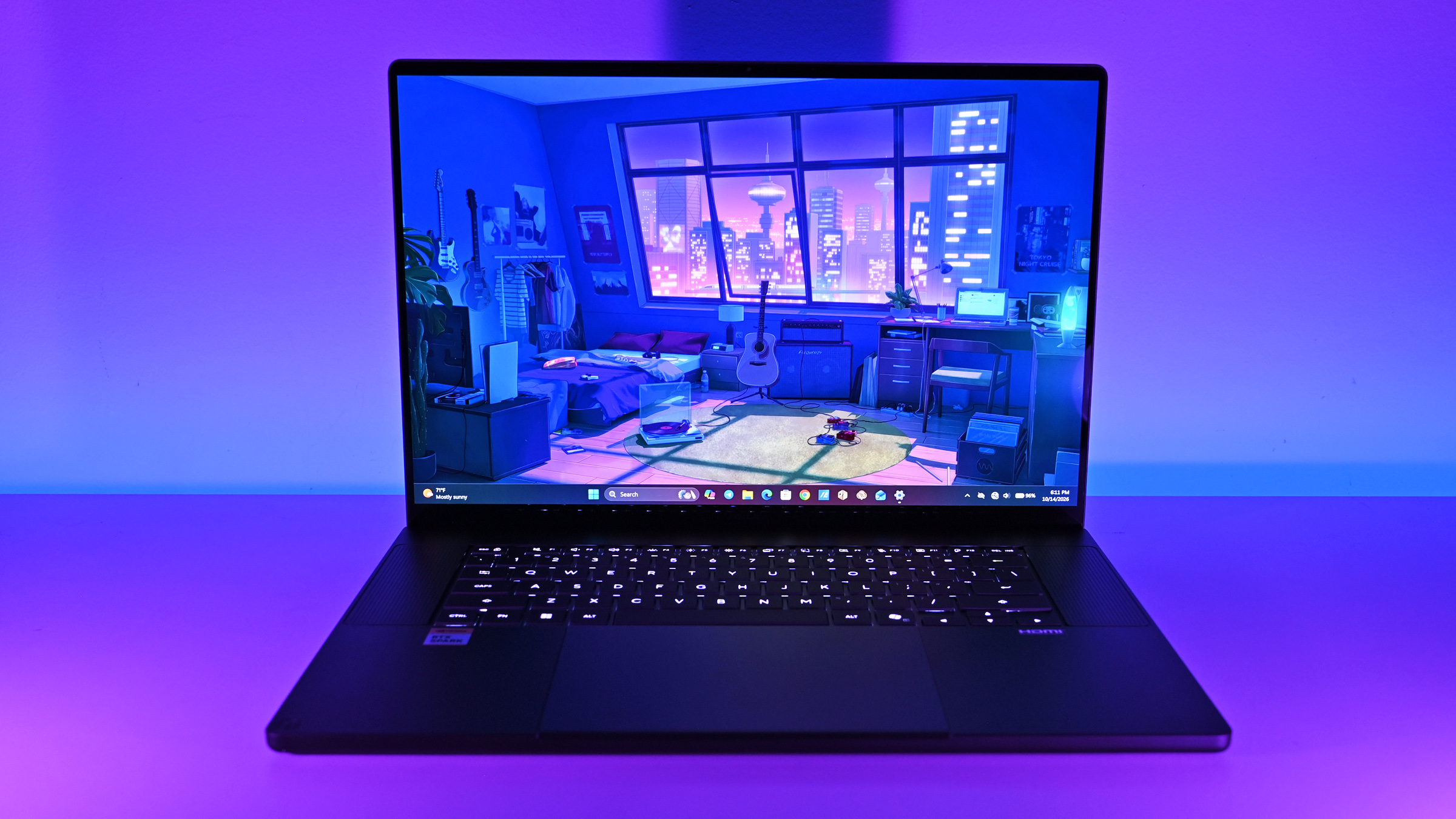 Ultrawide front shot of the open ASUS ProArt P16 laptop under purple ambient lighting, showing its backlit keyboard and vibrant anime room wallpaper.