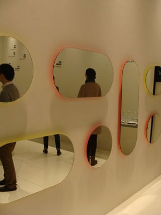 A wall with two rows of small mirrors of various oval shapes.