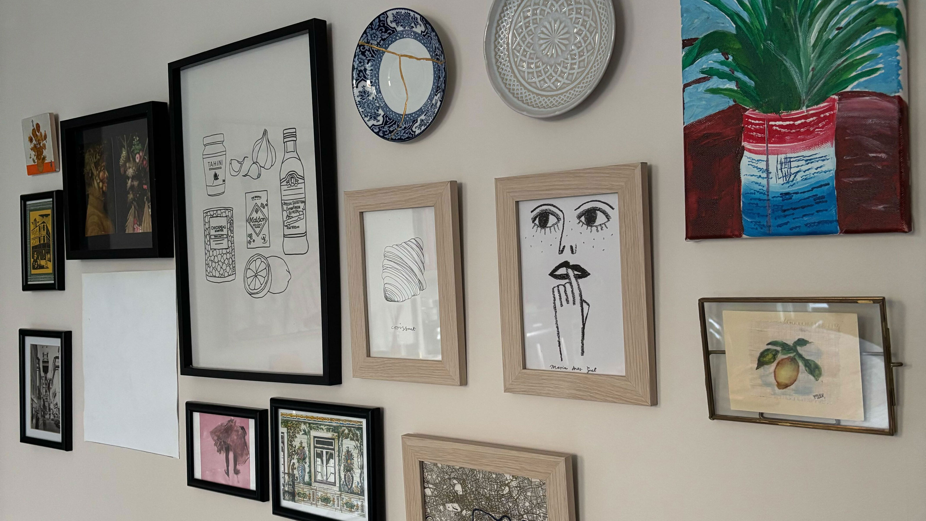 White wall with a mix of frames, plates and canvas on the wall