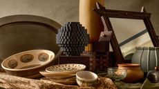 pieces from the Pierce and Ward x West Elm collection on a table including a mirror, vase, bowls and plates, and glassware