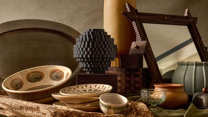 pieces from the Pierce and Ward x West Elm collection on a table including a mirror, vase, bowls and plates, and glassware