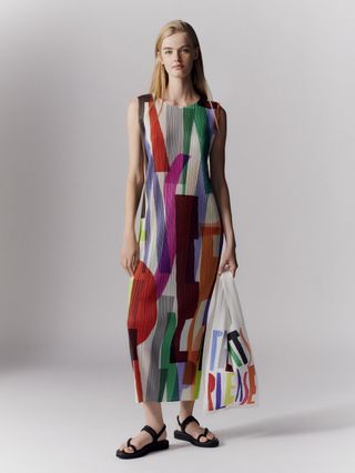 Woman in pleats please issey miyake colourful dress and bag
