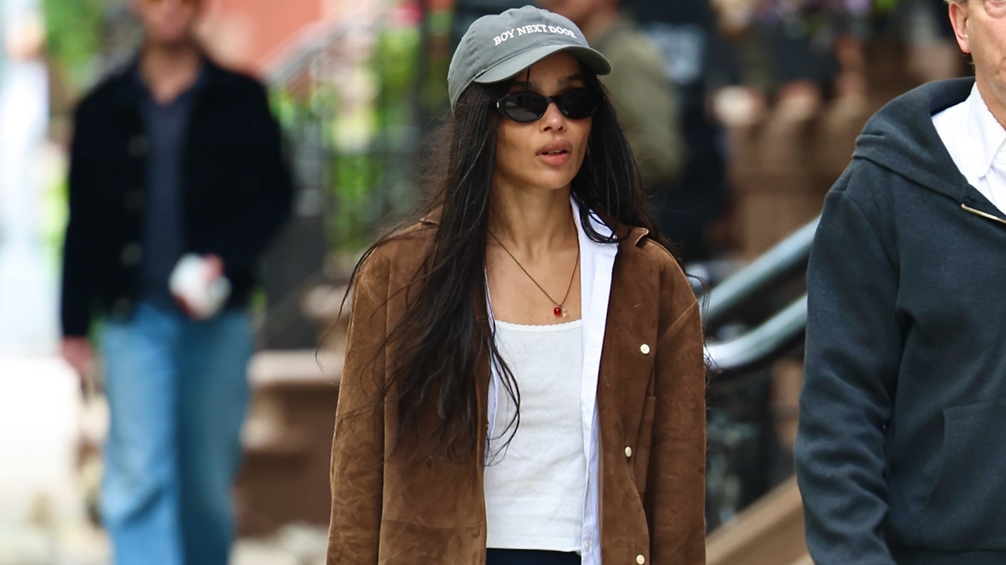 Zoe Kravitz wears a baseball cap, a white tank top and a suede jacket.