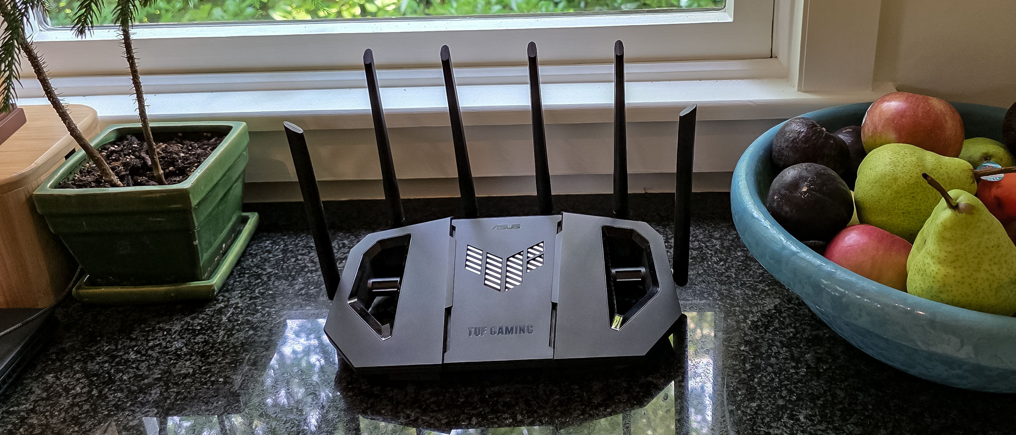 An Asus TUF Gaming BE6500 router on a windowsill.