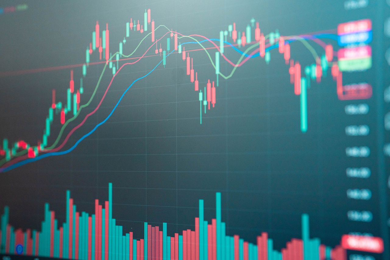 closeup of stock chart with red green and blue moving averages and red and green bars going up