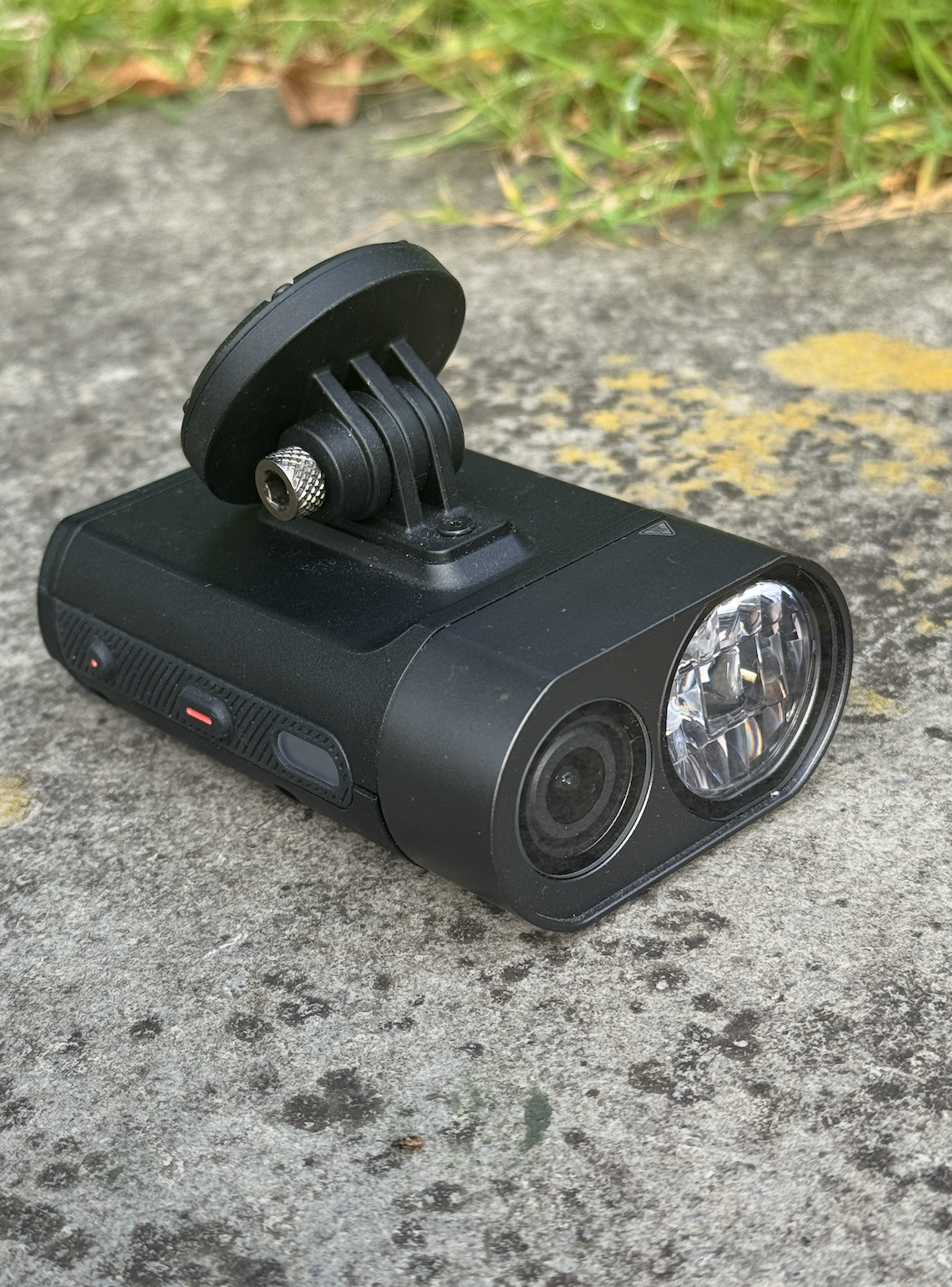 The Varia Vue unit sits on some concrete. You can see two small buttons on the side and the indicator LED lights