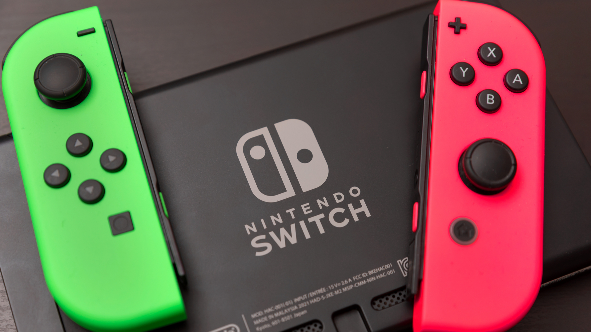 The green and pink Joy-Con sit on top behind the Switch