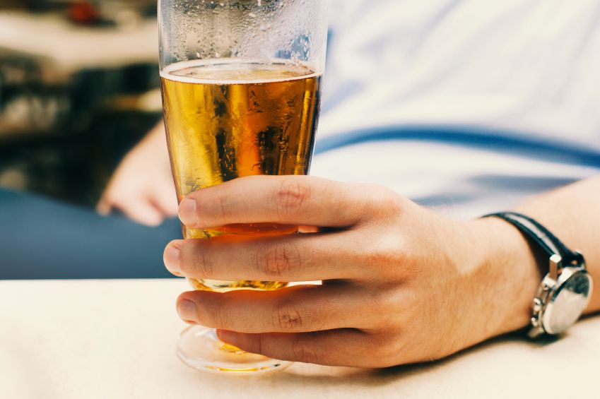 A young man holds a beer glass.