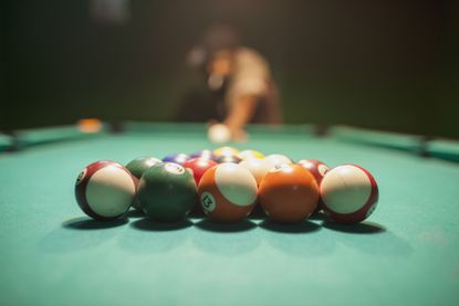 A pool table is set with balls ready to be broken. 