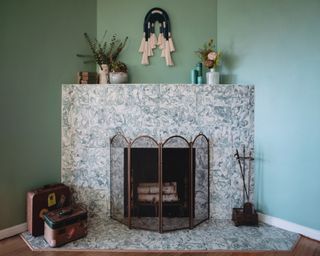 Corner fireplace with stone surround and wire cover. Green painted walls and decorative accents.
