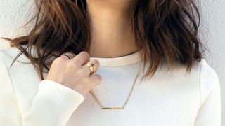 Girl in white against wall wearing AUrate jewelry