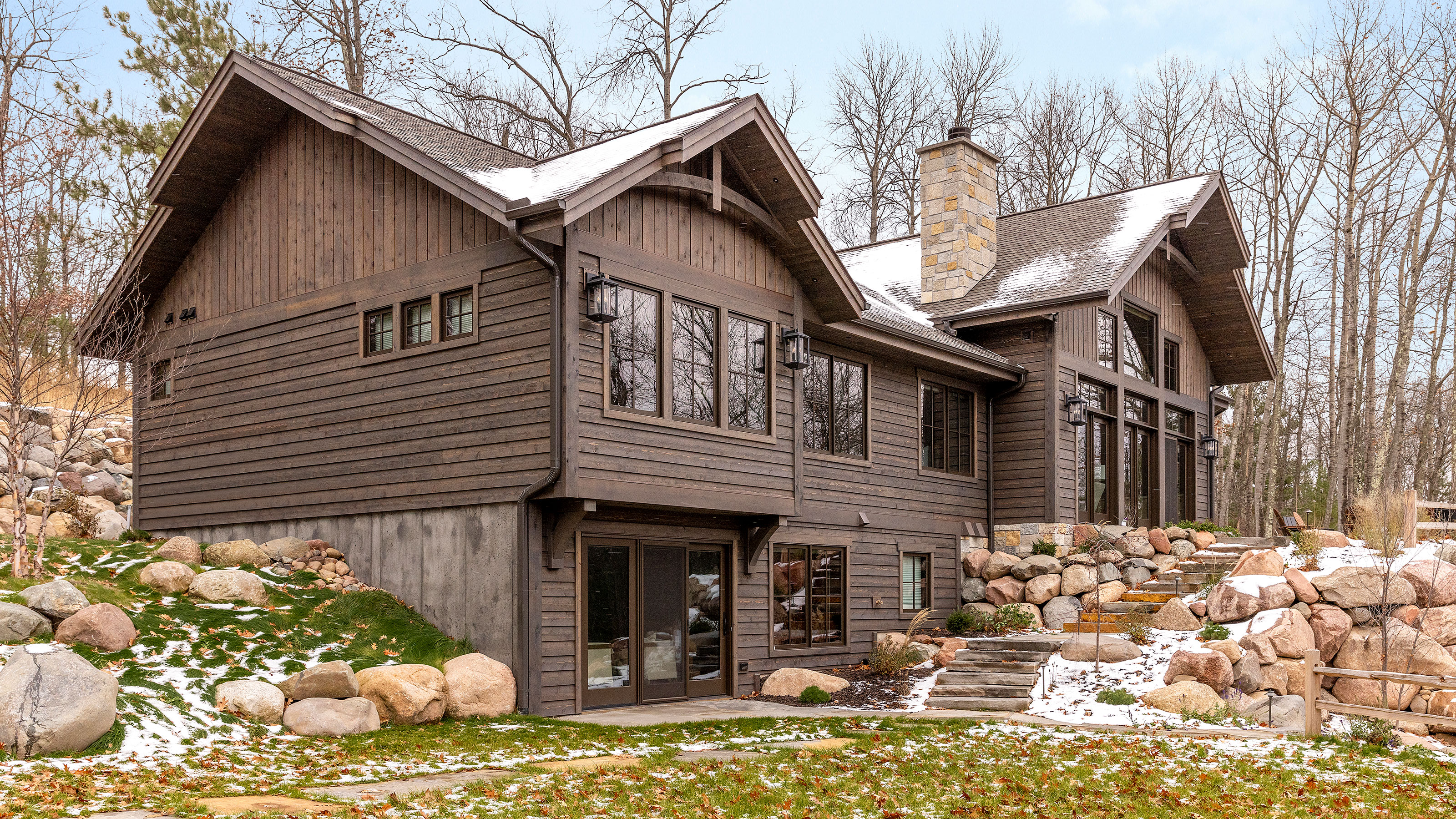 exterior of wooden cabin home in winter with snow and bare trees