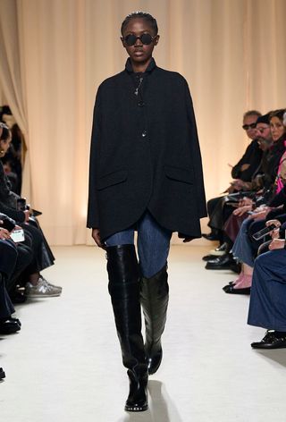 best riding boots shown in a photo from Bally's fall 2024 runway show with a model wearing a black coat, skinny jeans, and over-the-knee riding boots