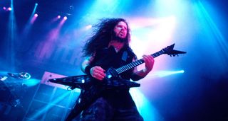 Dimebag Darrell riffs with Pantera circa 2001, on a stage backlit with blue and pink lights.