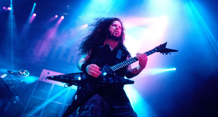 Dimebag Darrell riffs with Pantera circa 2001, on a stage backlit with blue and pink lights.