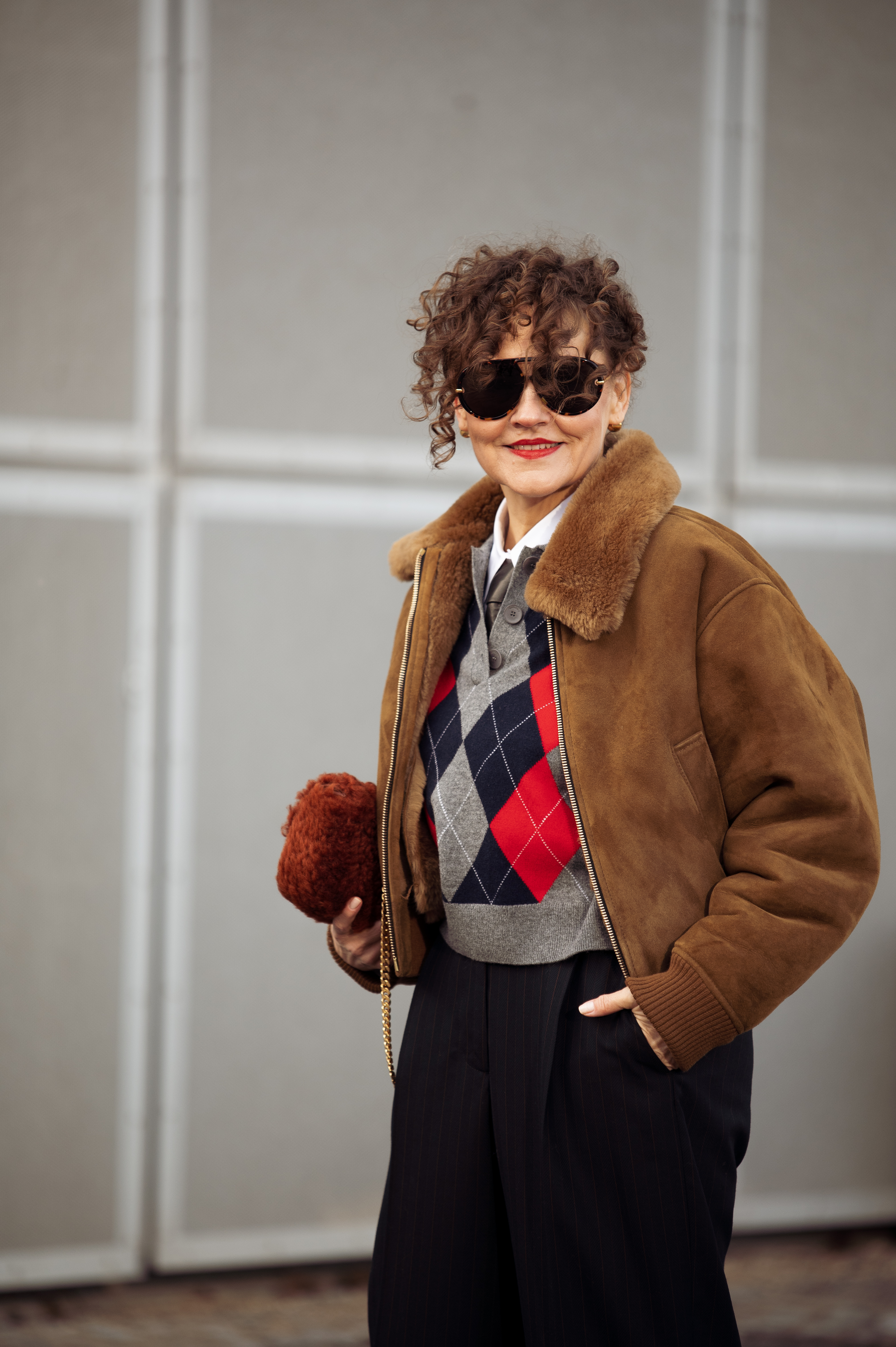 COPENHAGEN, DENMARK - FEBRUARY 1: Renia Jaz wears black pants, a grey, red, and black vest, a brown jacket, and a red bag outside TG Botanical during Copenhagen Fashion Week AW24 on February 1, 2024 in Copenhagen, Denmark. (Photo by Raimonda Kulikauskiene/Getty Images)