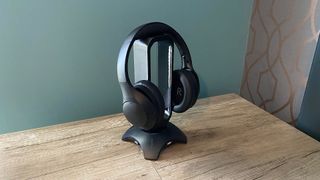 Happy Plugs Play Pro over-ear headphones hanging on a stand, on a wooden table