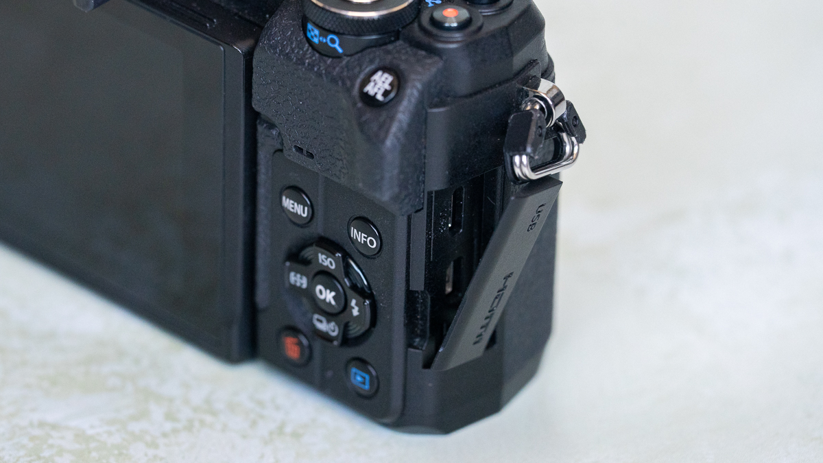 Olympus OM-D E-M10 Mark IV side view, showing the buttons on the rear and the micro-USB and HDMI ports.