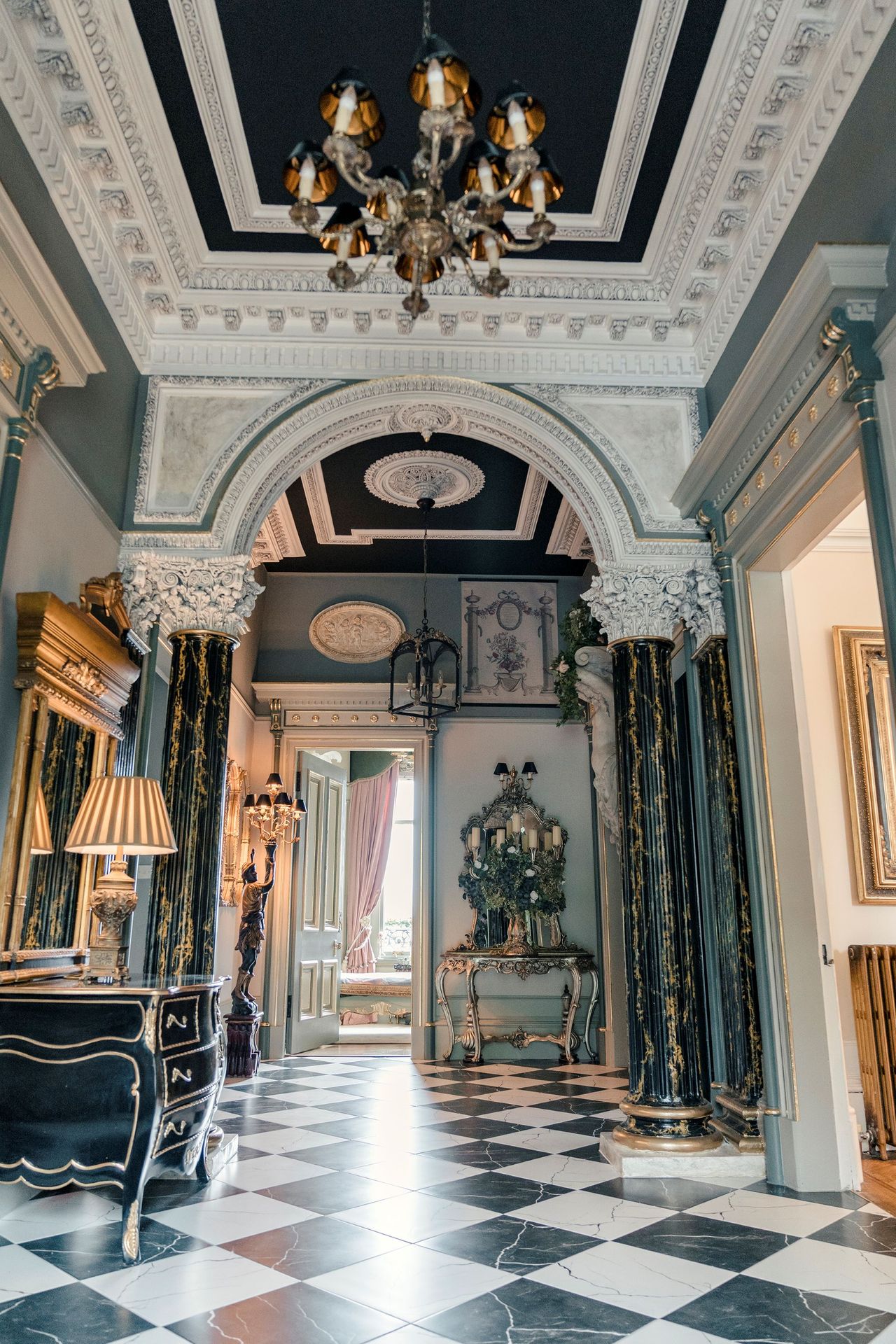 The upstairs hallway shows a chandelier hanging from the ceiling and scarlet carpet