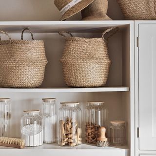 cream open shelving with glass storage and wicker baskets